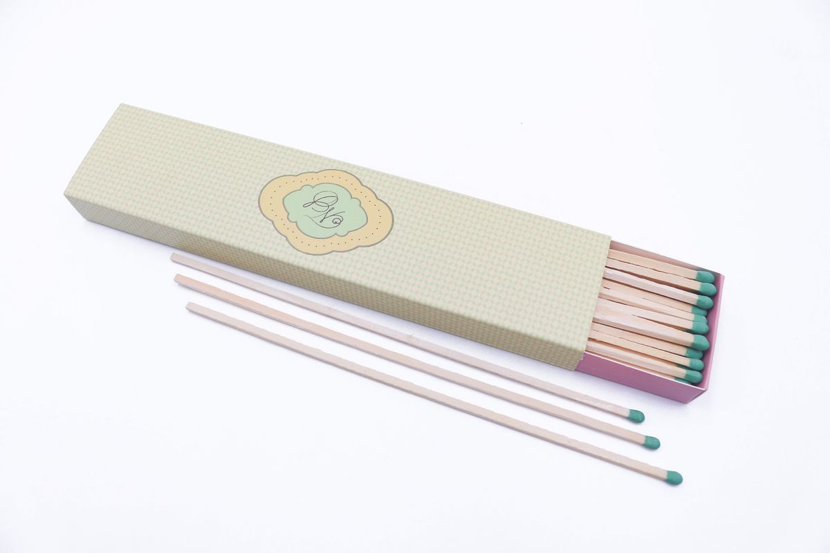 Angled view of a printed long matchbox with three extra long matches laid out in front