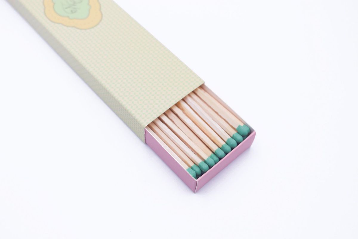 Open slide box of long safety matches showing green match heads in neat rows